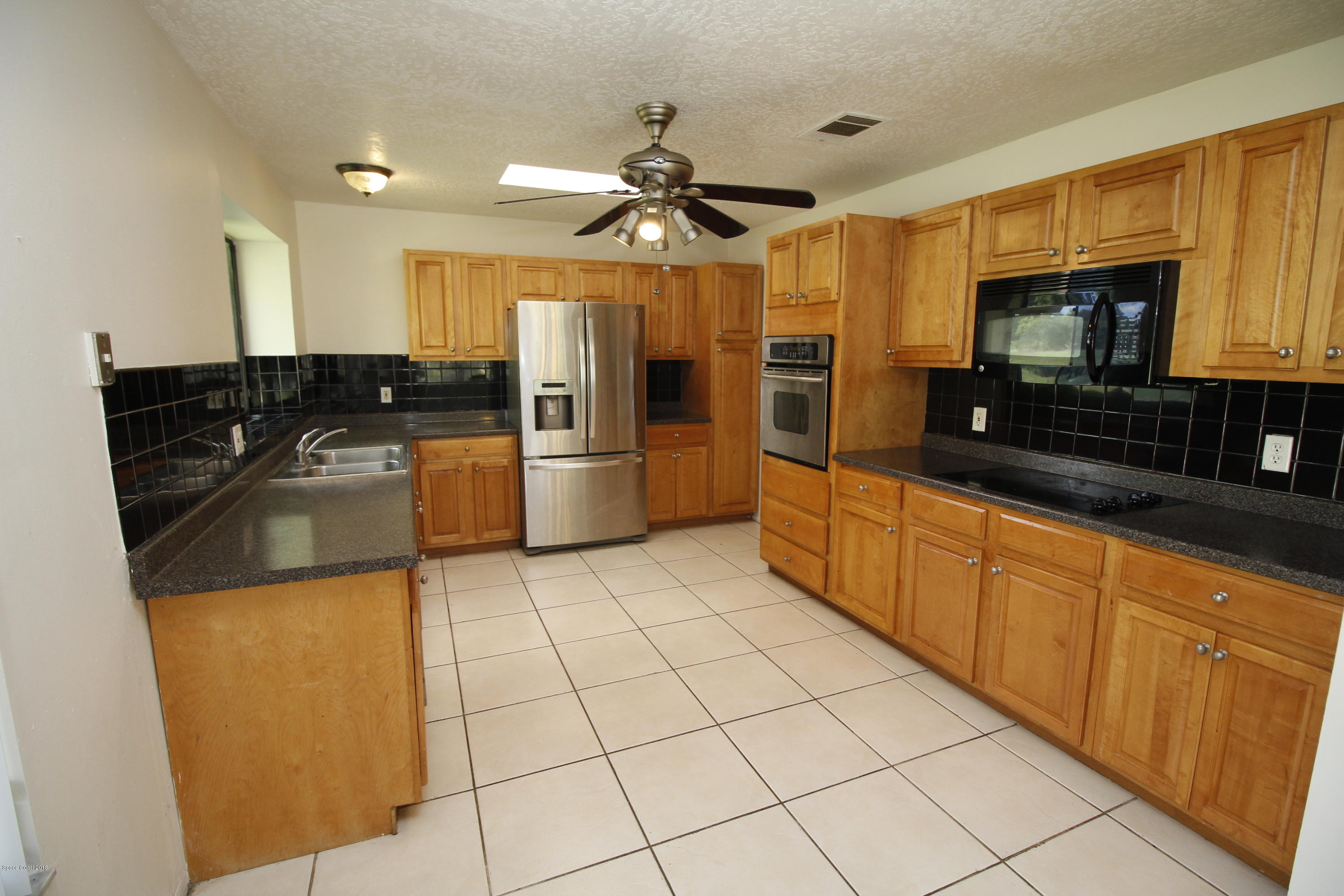 1302 Cherry Hills Road Northeast Palm Bay, FL 32905 - Photo 11 of 24 a kitchen with stainless steel appliances granite countertop a refrigerator a stove top oven a sink and dishwasher