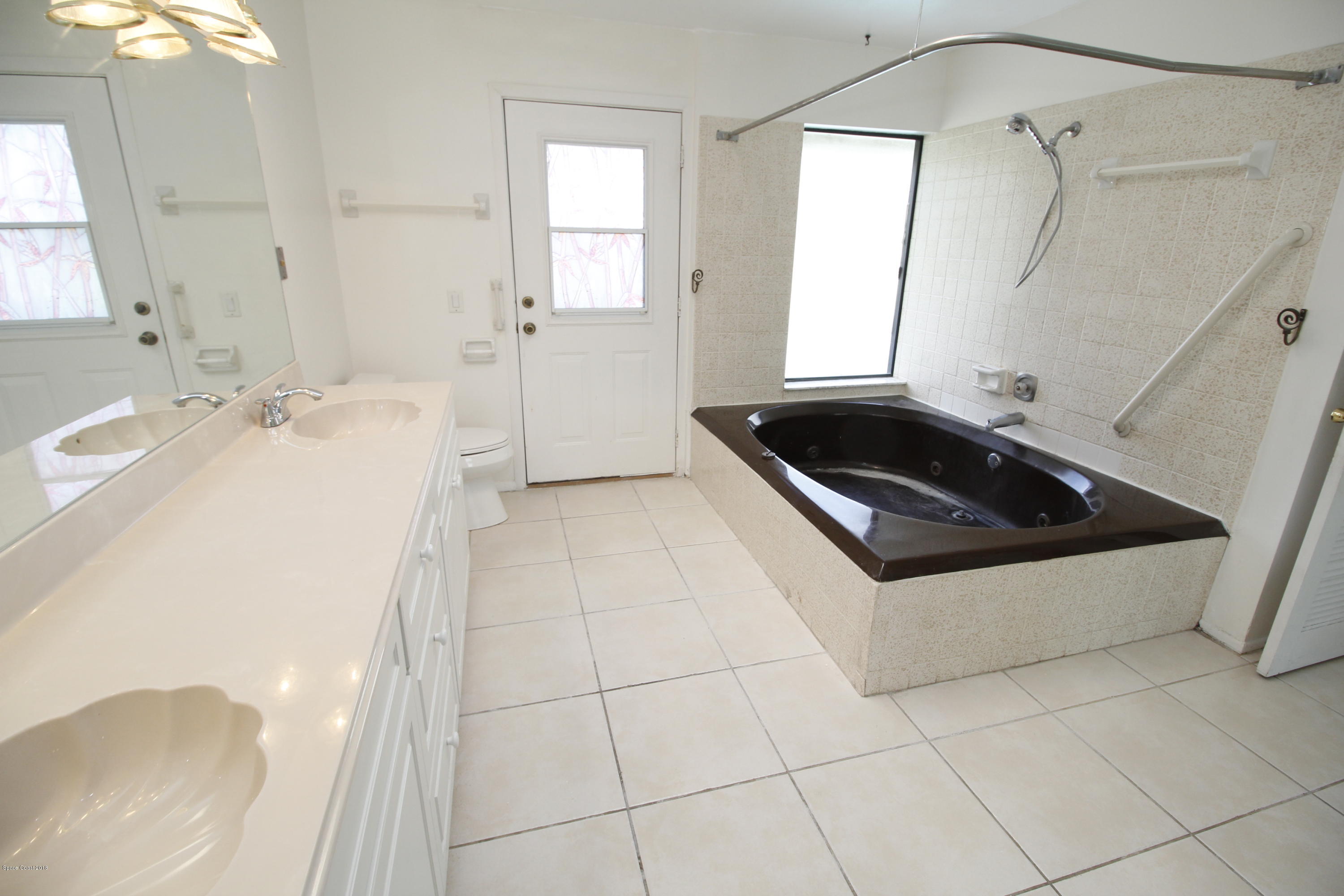 1302 Cherry Hills Road Northeast Palm Bay, FL 32905 - Photo 16 of 24 a bathroom with a sink a toilet a window and vanity