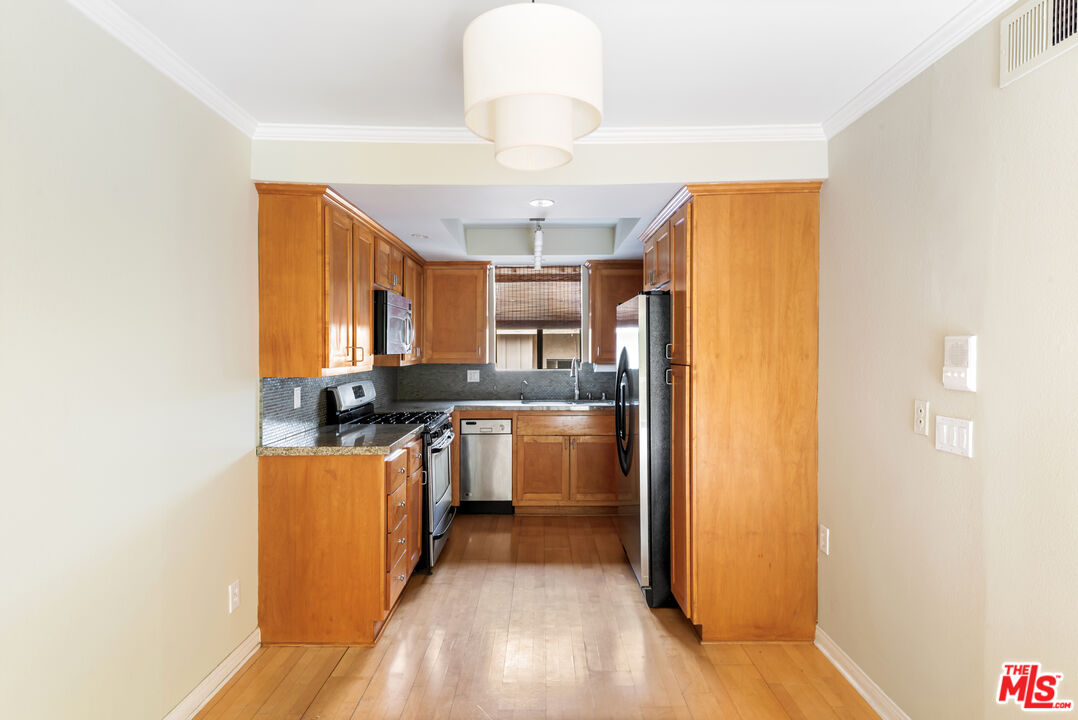 10671 Wilkins Avenue, Unit 5 Los Angeles, CA 90024 - Photo 9 of 28 a kitchen with stainless steel appliances granite countertop a refrigerator a sink dishwasher a stove and a dining table with wooden floor