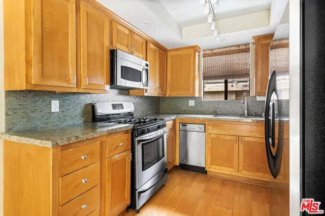 a kitchen with stainless steel appliances granite countertop a stove a sink and a refrigerator