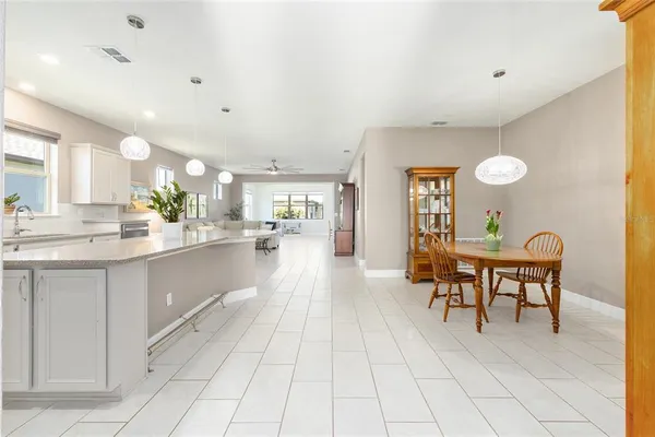 a view of a kitchen with dining area a chandelier fan and windows