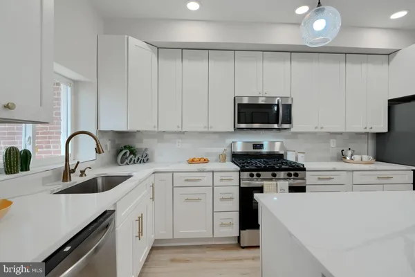a kitchen with stainless steel appliances granite countertop white cabinets a sink a stove and a refrigerator