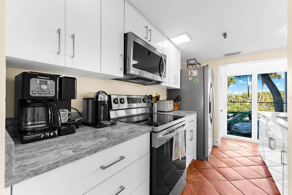 5000 Gasparilla Road, Unit 13A Boca Grande, FL 33921 - Photo 7 of 61 a kitchen with stainless steel appliances granite countertop a stove a sink and a microwave