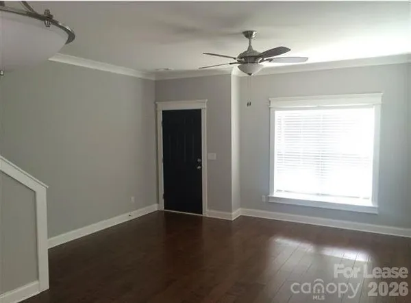 an empty room with wooden floor fan and windows