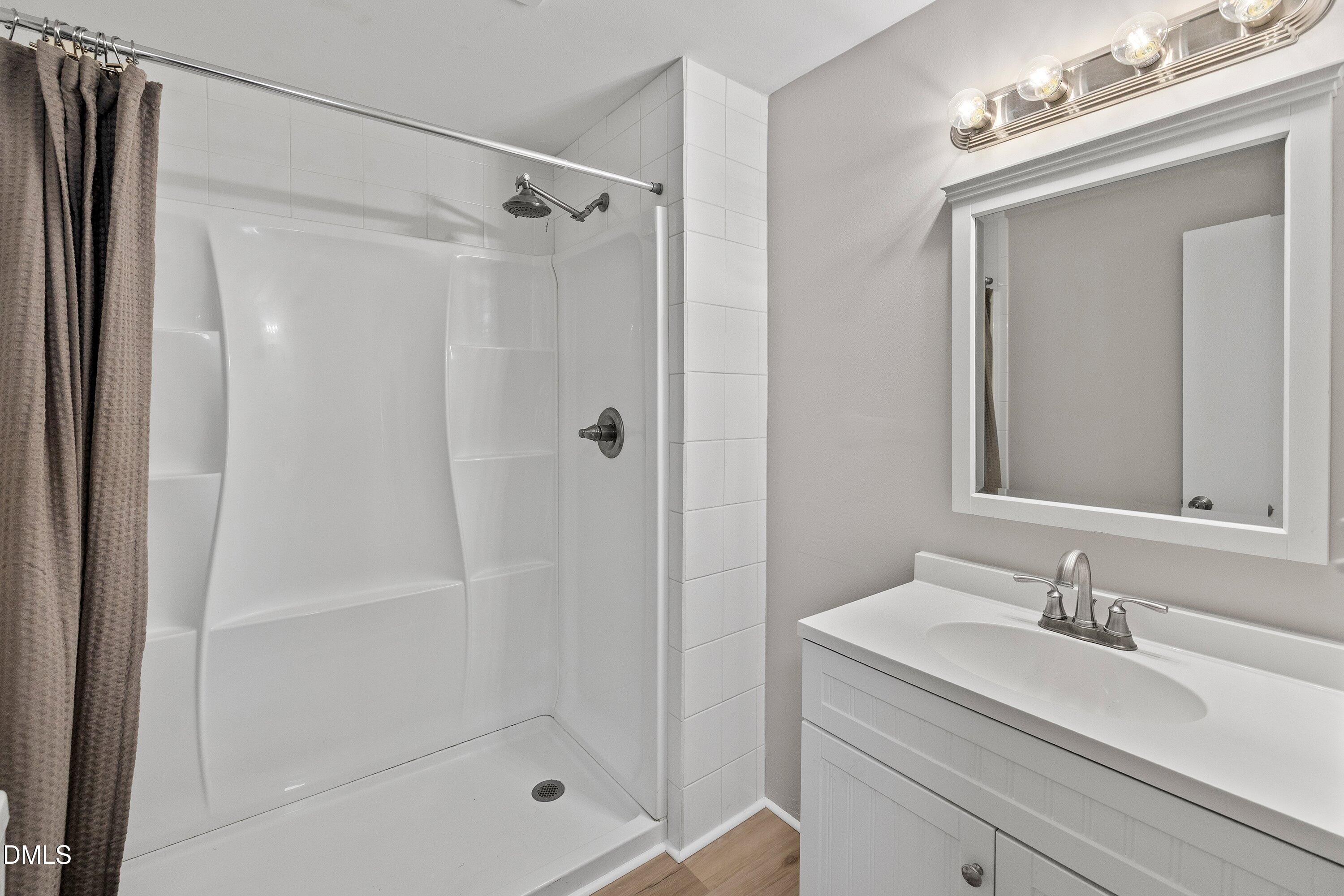 105 East I Street Erwin, NC 28339 - Photo 13 of 39 a bathroom with a granite countertop sink a mirror a glass door a shower and vanity