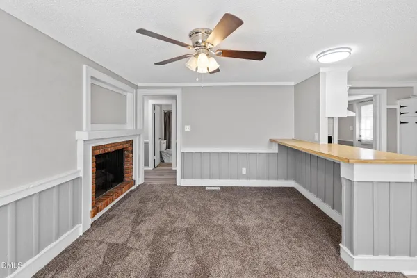 a view of an empty room with window and a kitchen