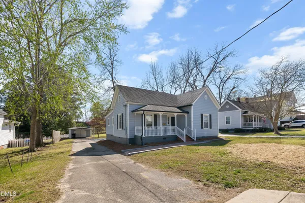 a front view of a house with a yard and large trees