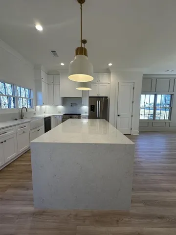 a large kitchen with kitchen island a stove a sink dishwasher a dining table and chairs with wooden floor