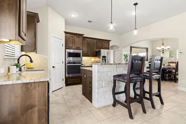 a kitchen with kitchen island granite countertop wooden cabinets and stainless steel appliances