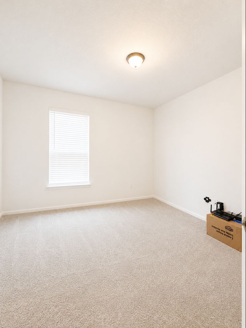 693 Durian Loop Buda, TX 78610 - Photo 12 of 27 A well-lit bedroom offering a blank canvas for personalization.