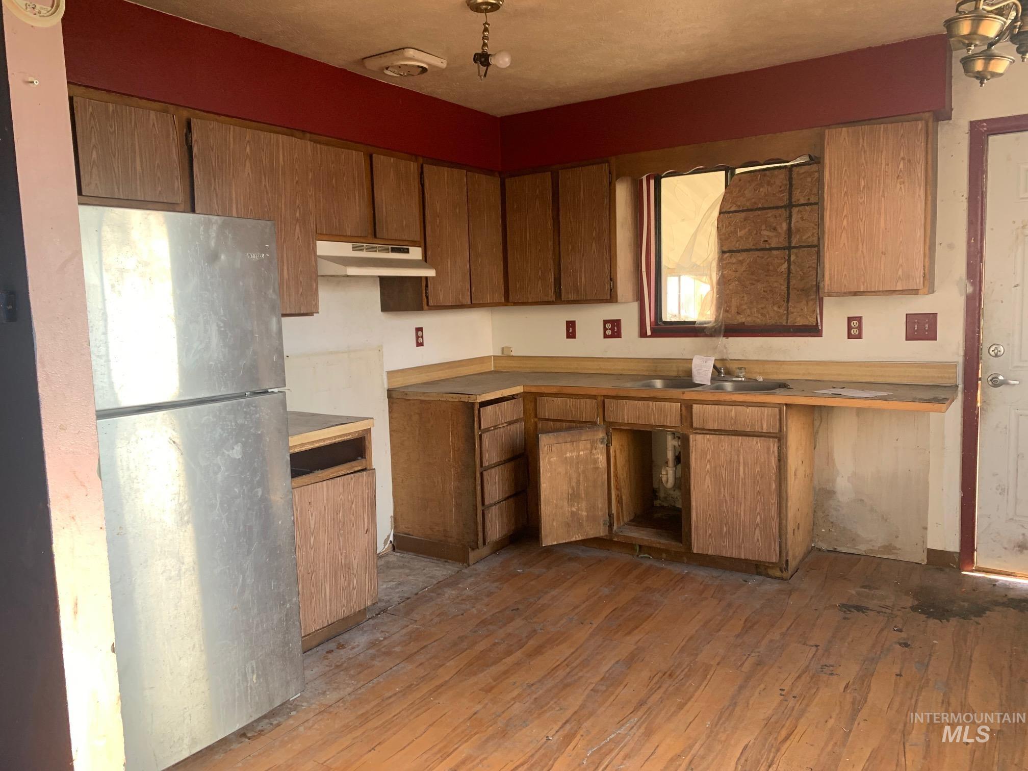 1435 Normal Burley, ID 83318 - Photo 6 of 9 Kitchen with freestanding refrigerator, dark wood finished floors, brown cabinets, light countertops, and under cabinet range hood