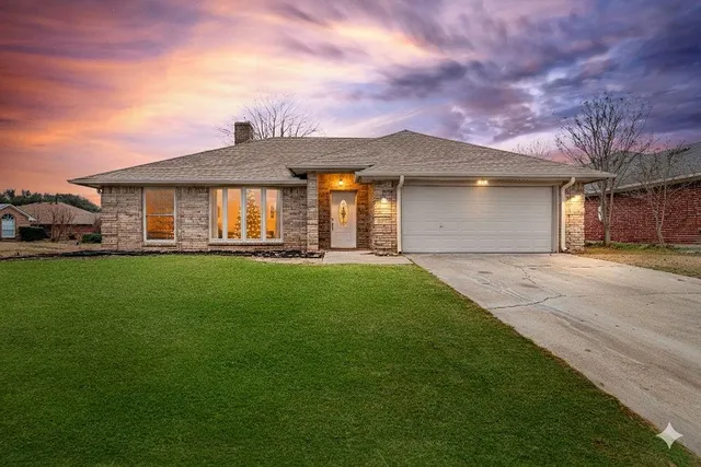 a front view of a house with a yard and trees