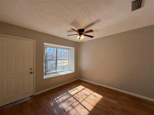 an empty room with windows and fan