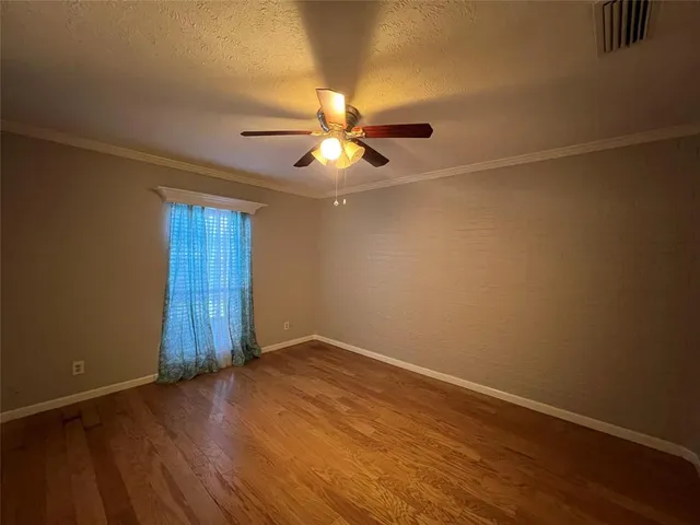 an empty room with wooden floor and chandelier fan