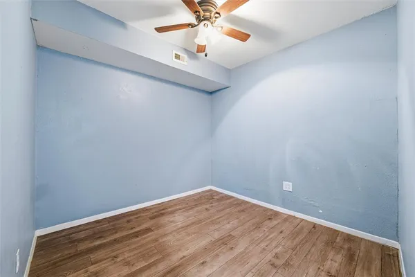 a view of an empty room with window and wooden floor