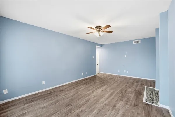 wooden floor in an empty room with a chandelier fan