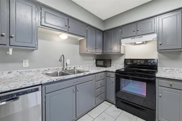 a kitchen with granite countertop stainless steel appliances a stove sink and cabinets