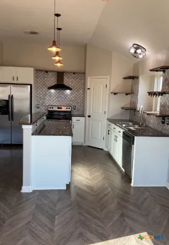 a kitchen with stainless steel appliances granite countertop a stove a sink dishwasher a refrigerator and white cabinets with wooden floor