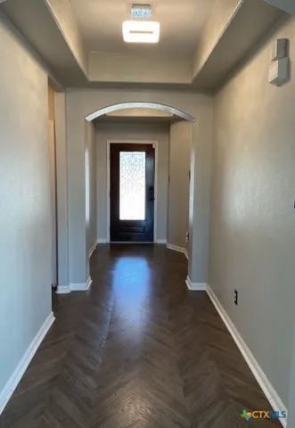 a view of a hallway with wooden floor and a living room