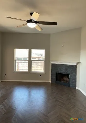 an empty room with wooden floor a fireplace and windows