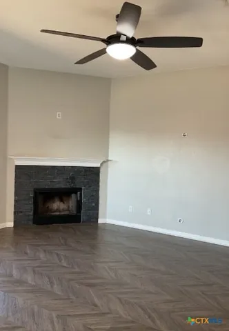 a view of an empty room with wooden floor fireplace and a window