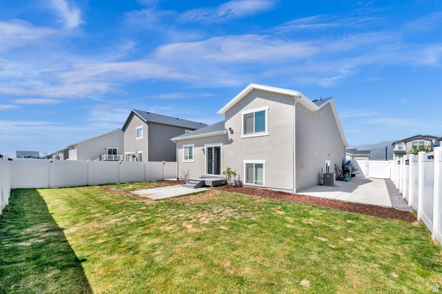 6120 North Sheps Ridge Road Eagle Mountain, UT 84005 - Photo 43 of 43 Rear exterior featuring a spacious lawn, white privacy fencing, and a concrete patio