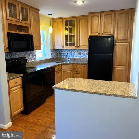 a kitchen with granite countertop wooden cabinets a refrigerator stove and sink
