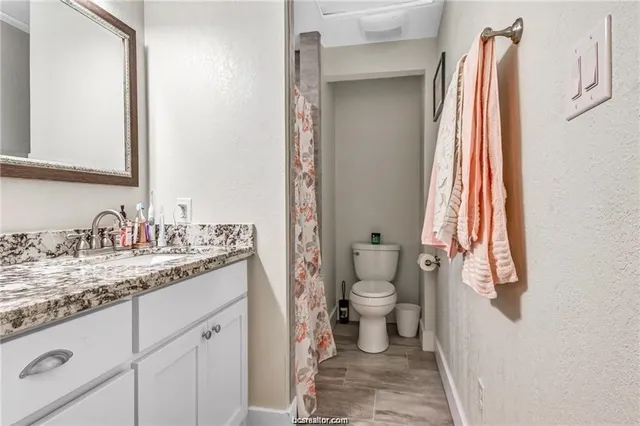a bathroom with a granite countertop sink and a toilet