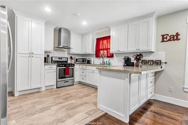 a kitchen with stainless steel appliances granite countertop a stove top oven a sink dishwasher and a refrigerator with wooden floor