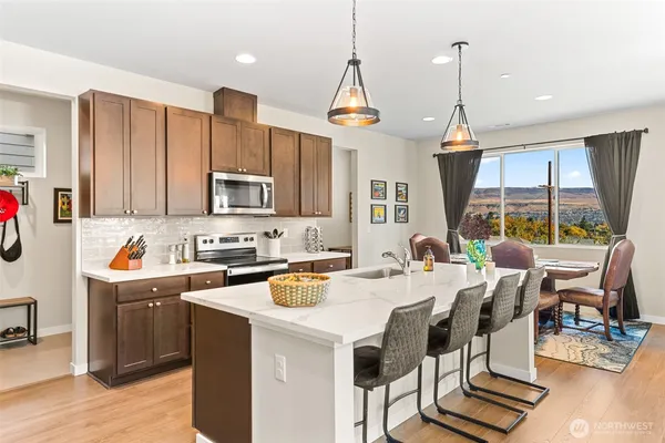 a kitchen with stainless steel appliances granite countertop a stove top oven a sink dishwasher and white cabinets with wooden floor