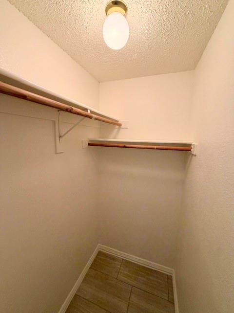 2604 Crix Lane Fort Worth, TX 76140 - Photo 10 of 13 Interior walk-in closet featuring light-toned walls, wood-finish tile flooring, and a flush mount ceiling light fixture