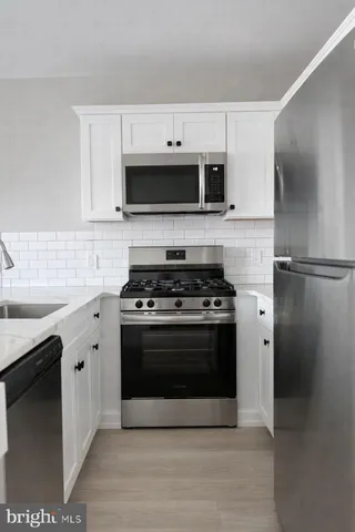 a white kitchen with stainless steel appliances and white cabinets