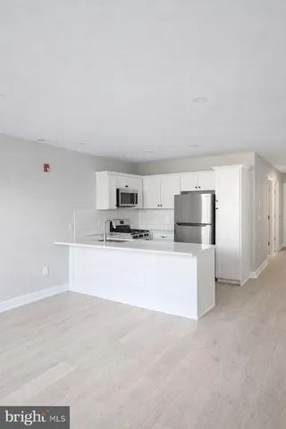 a large white kitchen with kitchen island a sink a stove and refrigerator