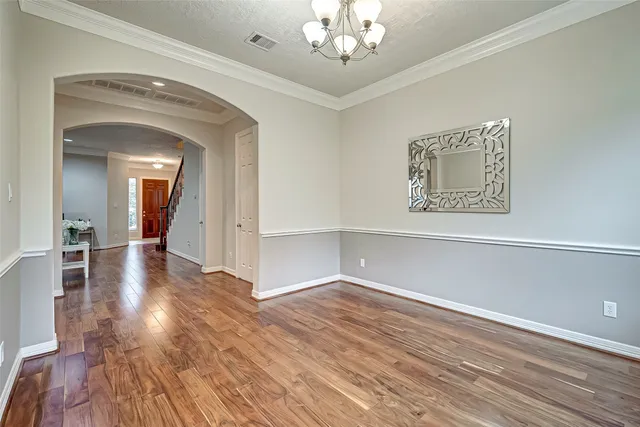 a view of a hallway with wooden floor and a chandelier