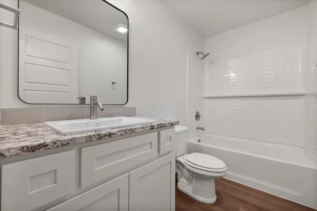 a bathroom with a granite countertop toilet sink and mirror