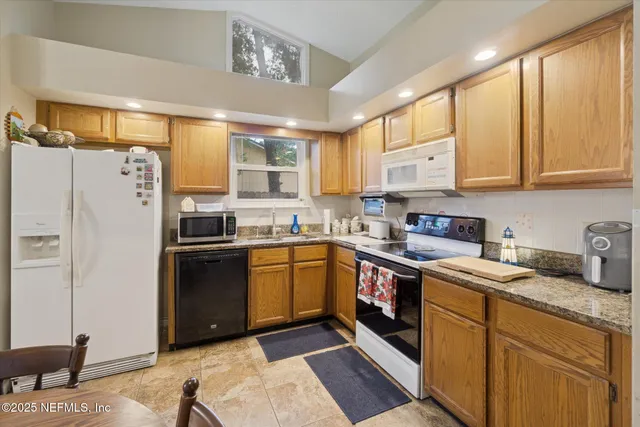 a kitchen with granite countertop a refrigerator stove top oven and sink