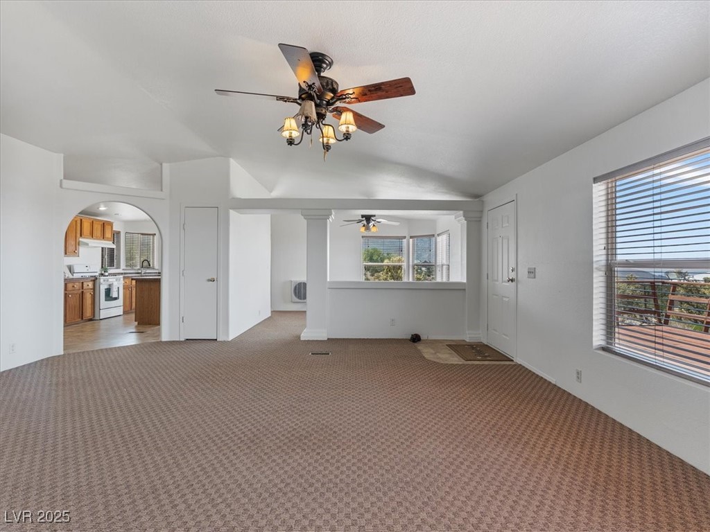 70 West Bonanza Road Las Vegas, NV 89124 - Photo 17 of 71 Unfurnished living room featuring ceiling fan, vaulted ceiling, plenty of natural light, and light carpet