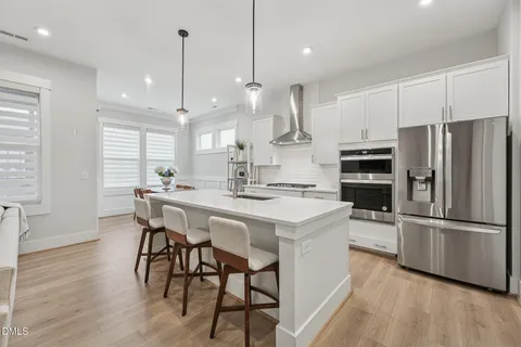 a kitchen with stainless steel appliances a dining table chairs stove refrigerator and microwave