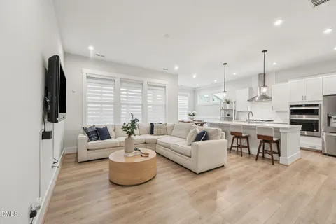 a living room with furniture kitchen view and a large window