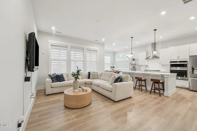 a living room with furniture kitchen view and a large window