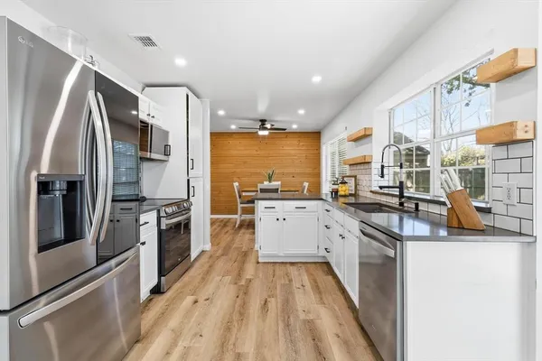 a kitchen with stainless steel appliances granite countertop a refrigerator a stove and a sink