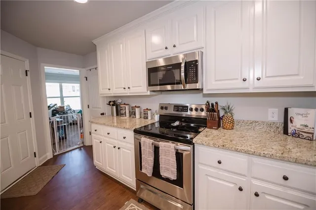 a kitchen with granite countertop white cabinets and stainless steel appliances