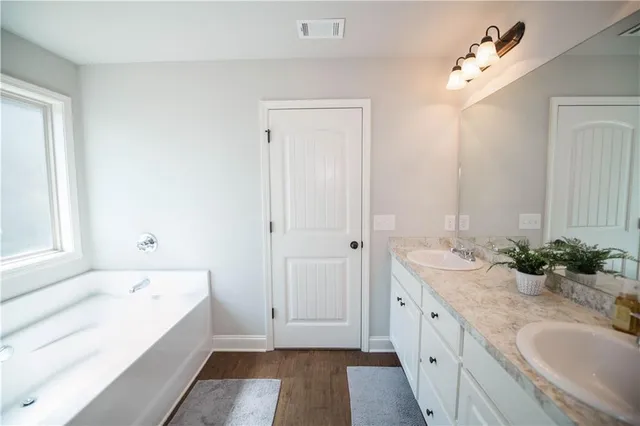 a bathroom with a tub sink and mirror