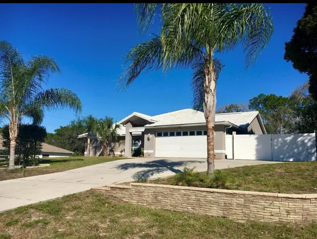 a view of a house with a yard and palm trees