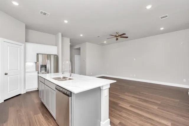 a view of kitchen island a sink a stove a refrigerator cabinets and wooden floor