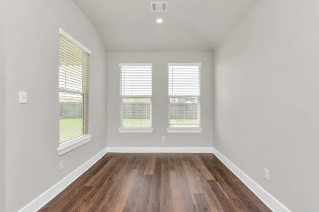 an empty room with wooden floor and windows