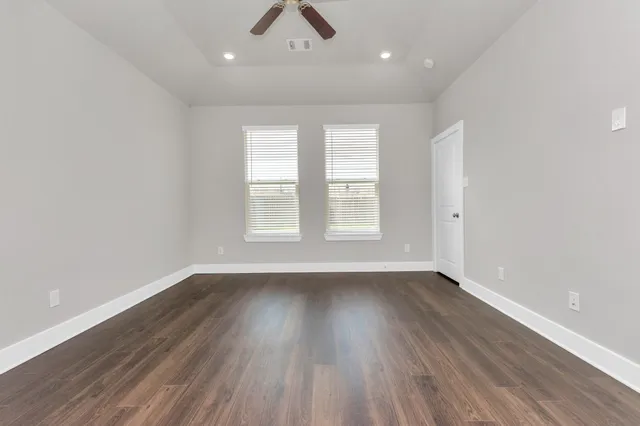an empty room with wooden floor and windows