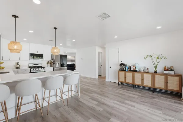 a kitchen with stainless steel appliances kitchen island granite countertop a stove a sink a refrigerator and white cabinets with wooden floor