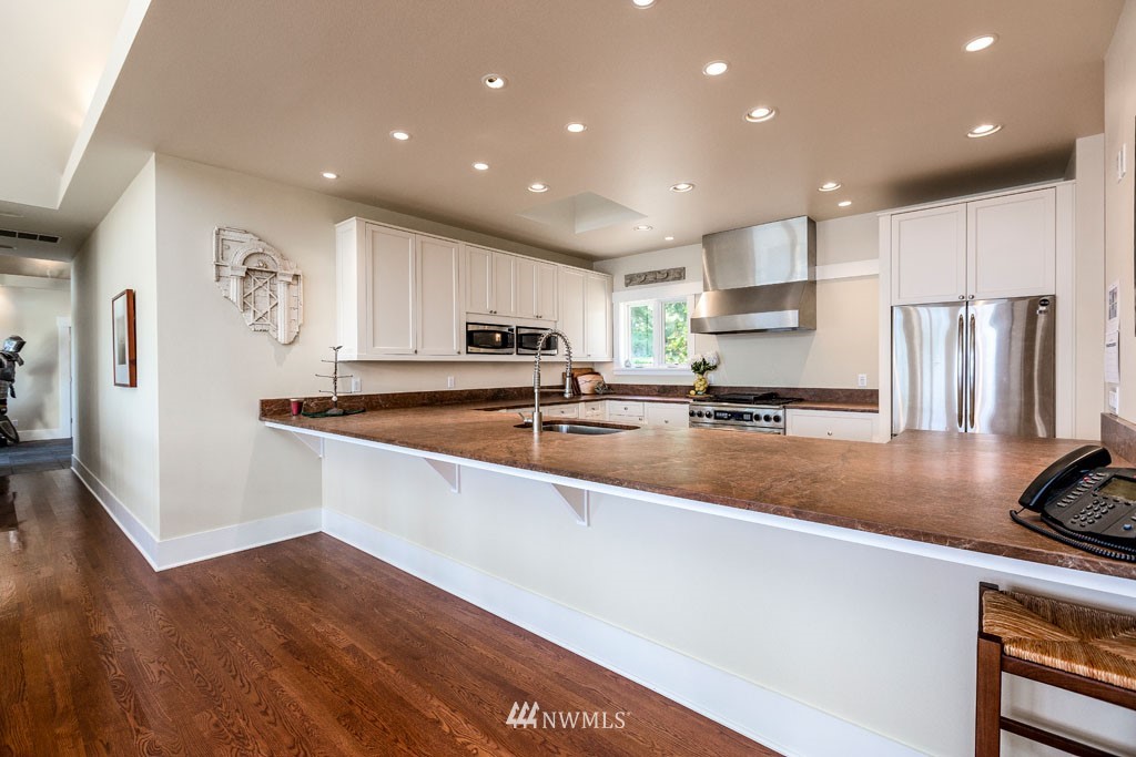 2397 Turn Point Road Friday Harbor, WA 98250 - Photo 9 of 25 a large kitchen with stainless steel appliances granite countertop a refrigerator a sink a stove a microwave and white cabinets with wooden floor