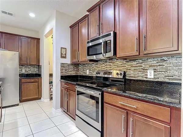 a kitchen with granite countertop stainless steel appliances a sink stove and cabinets